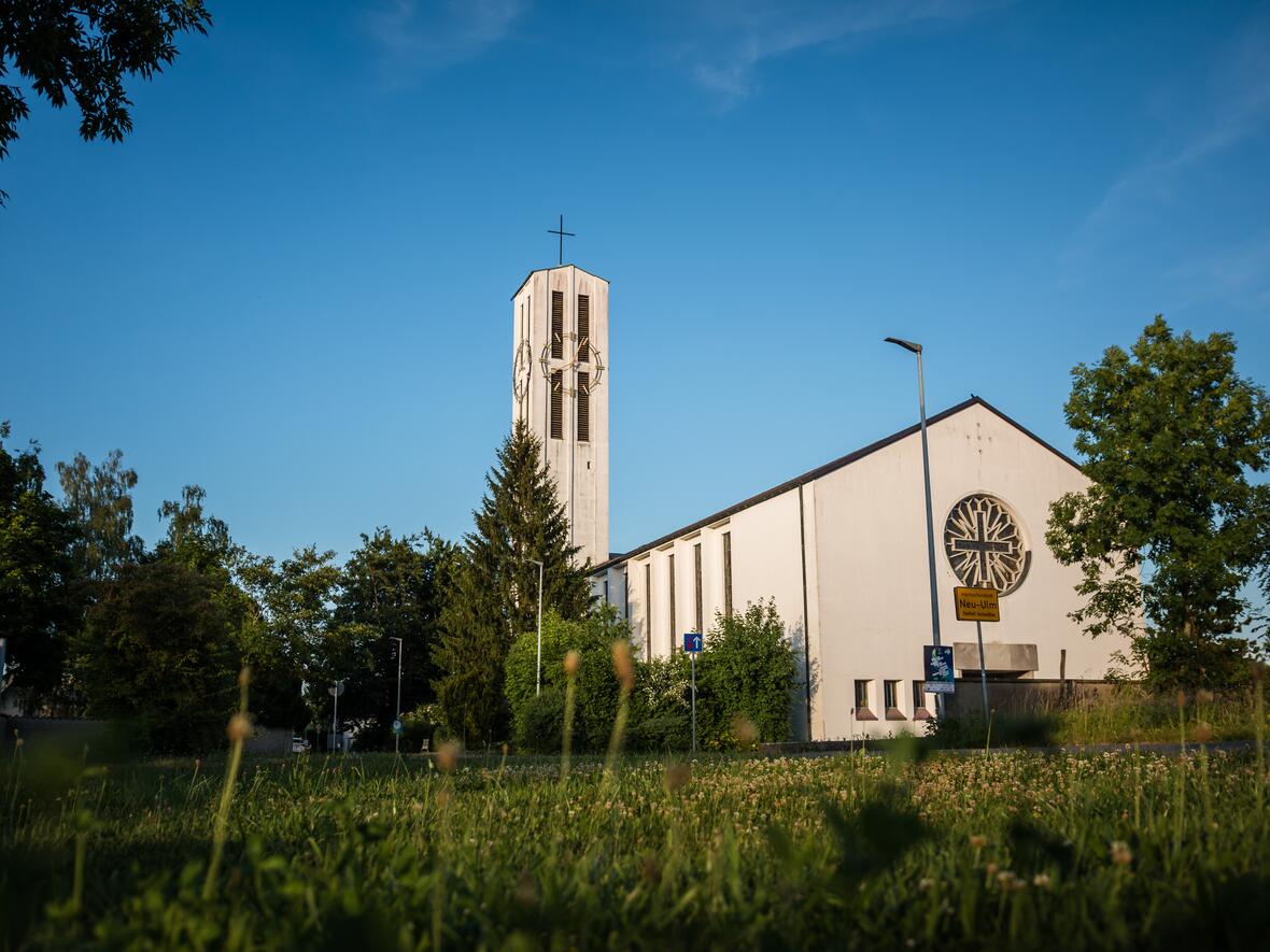 Kirche mit Kirchturm und umgebendem Grün in einer ruhigen Umgebung.